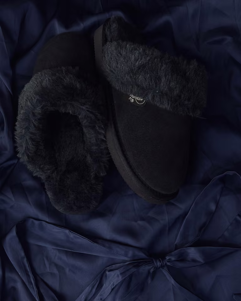 The Elysian in Midnight, charcoal shearling slippers resting on navy satin